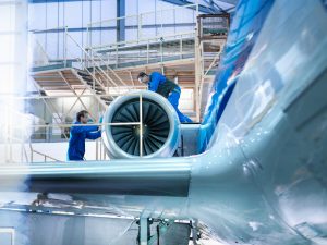 Engineers working on aircraft engine in aircraft maintenance factory